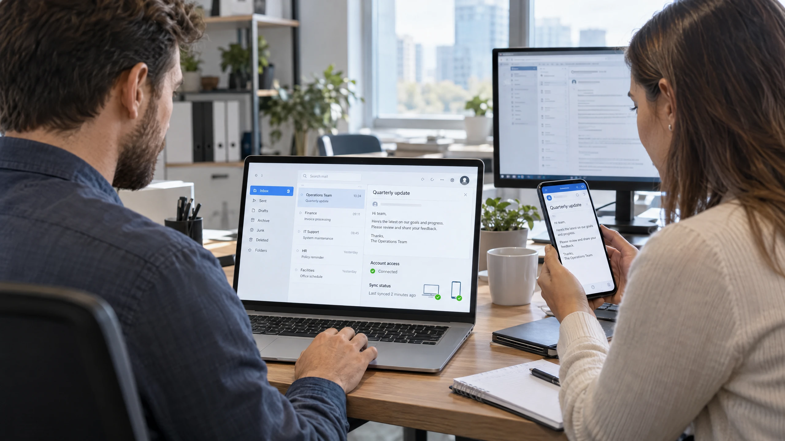Support specialist checking a business mailbox and device synchronisation across a laptop and phone (illustrative)
